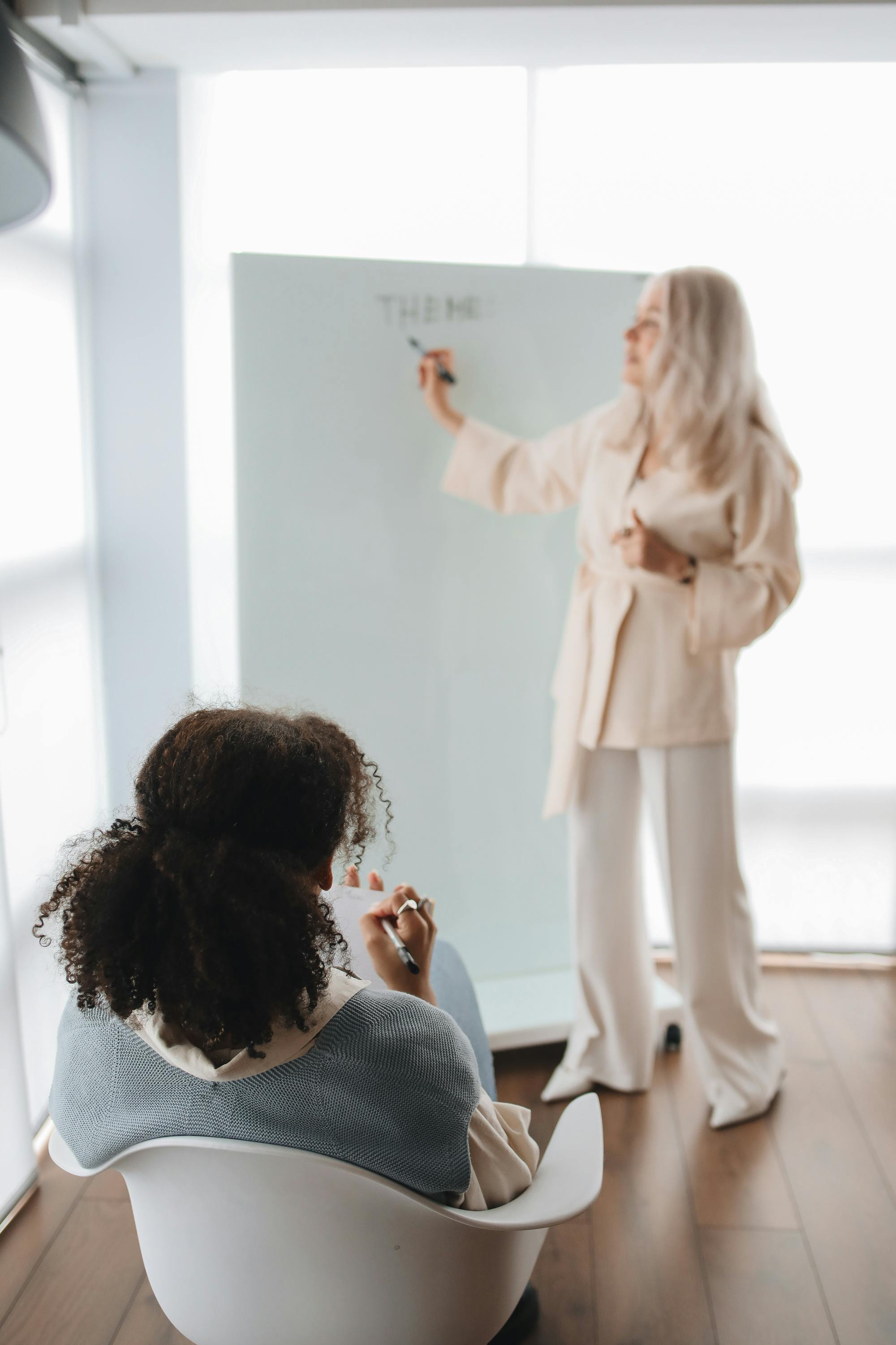 Two women engage in an interactive learning session with a whiteboard in a modern classroom.